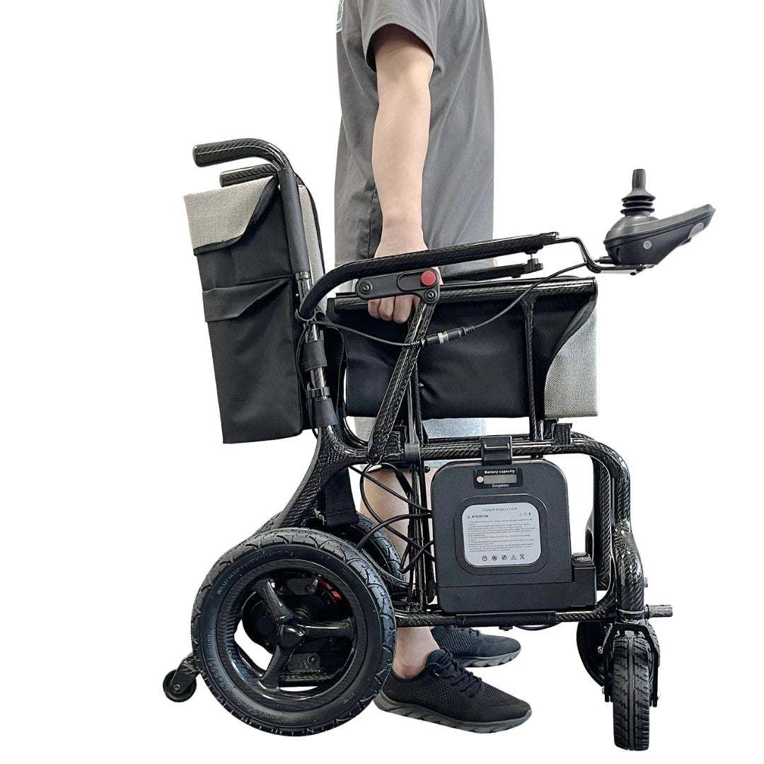 man carrying grey wheelchair with 1 hand